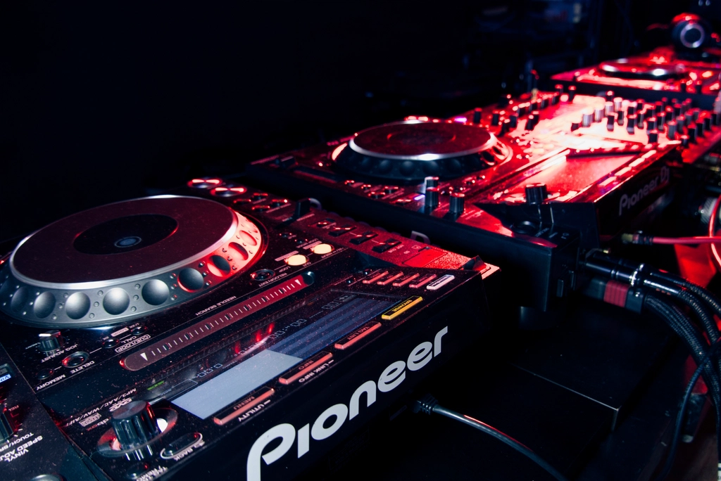 Illuminated DJ decks glowing red in a dark booth